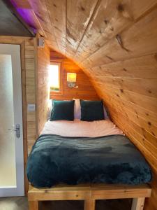 a bed in a room with a wooden wall at Smugglers Cove in Widows Row