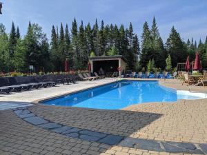 a swimming pool with chairs and a table and a person at Family escape w private hot tub in Lac-Superieur