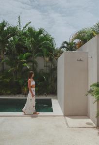 una mujer vestida de blanco caminando por una piscina en Designer 3BR Villa Tropical Stay Near Canggu, en Kerobokan