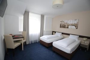 a hotel room with two beds and a desk at Wellness penzion U GIGANTU in Plzeň