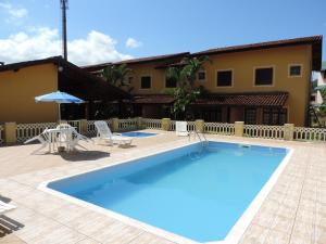 una grande piscina con sedie e una casa di Residencial Doce Marina a Caraguatatuba