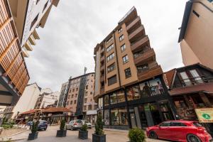 a red car parked in front of a building at Gorski Elegance Apartments Premium in Zlatibor