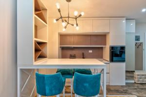 a kitchen with a table and blue chairs at Gorski Elegance Apartments Premium in Zlatibor