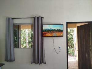 a flat screen tv on a wall next to a window at Chalé do Ypê 1 in Pirenópolis