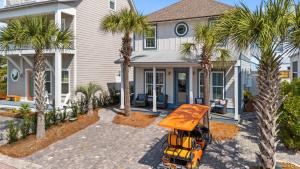 ein gelber LKW, der vor einem Haus mit Palmen parkt in der Unterkunft Coastal Getaway w Golf Cart Beach Gear Villa Galini by AvantStay in Santa Rosa Beach