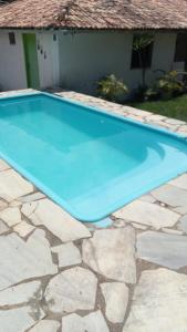 a blue swimming pool in front of a house at Sitio pousada Santo Antônio in Itaporanga dʼAjuda
