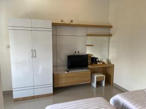 a bedroom with a tv and a white cabinet at Backyard Guest House in Banjar