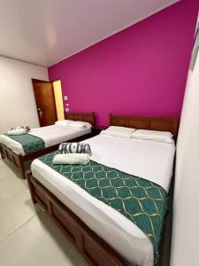 2 camas en una habitación con una pared púrpura en Apartahotel Caribe Diez, en San Andrés