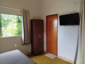 a bedroom with a wooden door and a television at Chalé do Ypê 2 in Pirenópolis