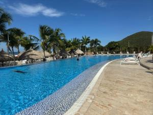a large swimming pool with chairs and palm trees at Samaria Top Penthouse Frente al Mar in Gaira