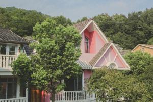 杭州杭州茶香丽舍旅居民宿的前面有一棵树的粉红色房子