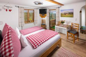 a bedroom with a bed with a red and white checked blanket at Pension Scheuerbichl in Bischofswiesen