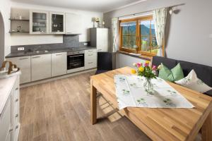 a kitchen and living room with a table with flowers on it at Pension Scheuerbichl in Bischofswiesen