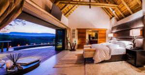 a bedroom with a large bed and a balcony at AM Lodge, AM Villa, AM Spa - Hoedspruit in Hoedspruit