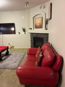 a red leather couch in a living room with a fireplace at Unique home services in Bélanger