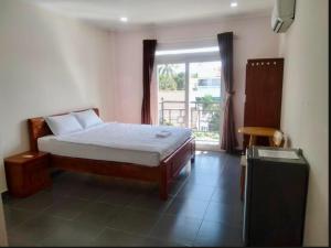 a bedroom with a bed and a large window at Aloha Hotel Mũi Né in Ấp Thiện Sơn