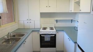 Una cocina blanca con estufa y fregadero. en Mountain Views Cedar Cottage, en Blackheath 15 fotos más