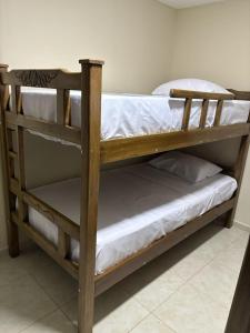 a wooden bunk bed with white sheets on it at Apartamentos KARS in Ríohacha