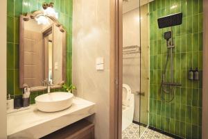 a green tiled bathroom with a sink and a shower at Samson Soleil Hotel in Sầm Sơn +42 photos