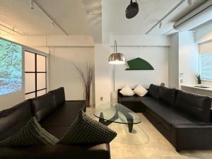 sala de estar con sofá negro y mesa de cristal en GalleryInn Fuji, Shibuya, en Tokio