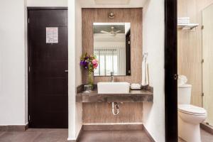 a bathroom with a toilet, sink and mirror at Aspira Hotel Playa del Carmen in Playa del Carmen
