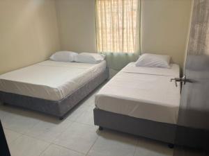 two twin beds in a room with a window at Apartamentos KARS in Ríohacha