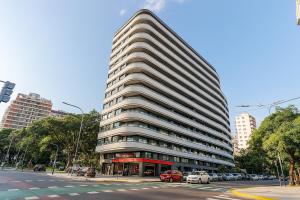 a tall building with cars parked in front of a street at HUB Apart Nuñez in Buenos Aires