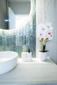 a bathroom with a sink and flowers on a counter at CHANTTAL Luxury - AMZEI in Bucharest +25 photos