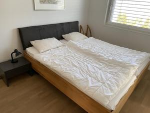 a bed with white sheets and pillows on it at Panorama View - CharmingStay in Flumserberg