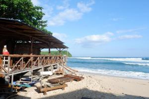 a beach with a hut and chairs and the ocean at Santai Guesthouse Balangan in Uluwatu