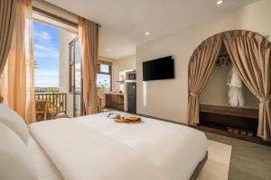 ein Schlafzimmer mit einem großen weißen Bett und einem Balkon in der Unterkunft Poetic Riverside Villa - Steps to Hoi An Night Market in Hoi An