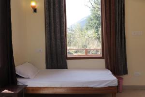 una cama en una habitación con ventana en By The Way, en Manali