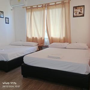 Dos camas en una habitación con ventana. en Bossa Nova - casa de descanso, en Santa Marta