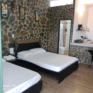 Dos camas en una habitación con pared de piedra. en Bossa Nova - casa de descanso, en Santa Marta
