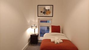 a small bedroom with a red bed and a window at Cohost Partners 3 Bed Apartment in Warrington in Warrington