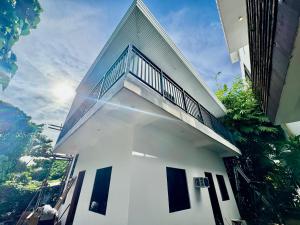 a white house with a balcony on top of it at Cozy Family Studio - Ronaldos Inn Twinex Suite in General Luna