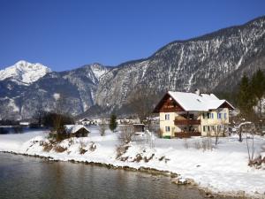 une maison dans la neige à côté d'une rivière dans l'établissement Haus Bergblick, à Obertraun