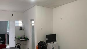 Zimmer mit einer weißen Wand, einem TV und einem Kühlschrank. in der Unterkunft Apto de temporada no litoral Piauí in Parnaíba