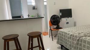 ein Schlafzimmer mit zwei Hockern, einem Bett und einem TV in der Unterkunft Apto de temporada no litoral Piauí in Parnaíba