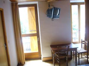 a dining room with a table and a television on the wall at Le Relais du Lac in Le Lauzet-Ubaye
