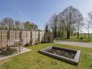 a backyard with a table and a pond in the grass at Oldwyche Barns in Warwick