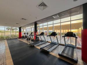 Modern High-Floor 1BR Apartment with Balcony, Pool Access & Golf Course View, Up to 4 Guests, by Stayfinity في دبي: صالة ألعاب رياضية مع أجهزة المشي وأجهزة بيضاوية