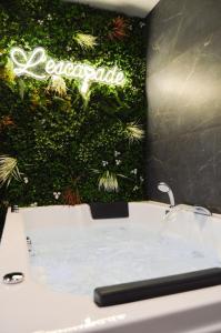 a bathroom with a bathtub and a green wall at L'Escapade - Love room & spa in Haguenau