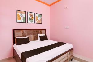 a bedroom with a large bed with pink walls at Hotel O SK in Sītāpur