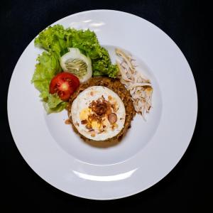 ein weißer Teller mit einem Ei und Salat in der Unterkunft Forrest Cafe & Wisata Berkuda in Jengkol