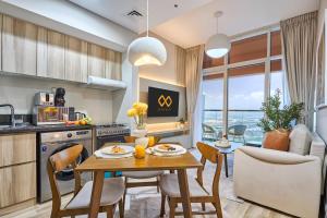 Modern High-Floor 1BR Apartment with Balcony, Pool Access & Golf Course View, Up to 4 Guests, by Stayfinity في دبي: مطبخ وغرفة طعام مع طاولة وكراسي
