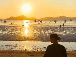 a woman standing on the beach watching the sunset at Suites by Eco Hotels in El Nido