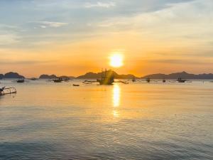 a boat in the water at sunset at Suites by Eco Hotels in El Nido