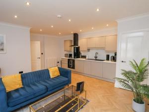 a living room with a blue couch and a kitchen at The Salisbury 1 Bed Classic Apartment in Scarborough