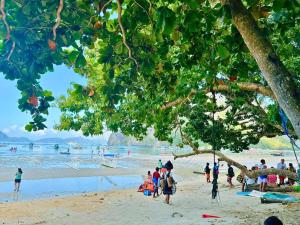 a group of people on a beach with a tree at Suites by Eco Hotels in El Nido